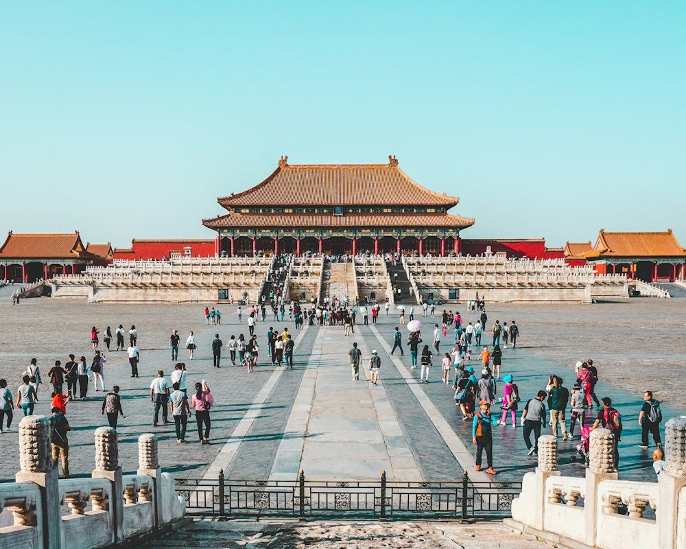 Visitors crossing the great stone courtyard of the Forbidden City in Beijing under a clear sky