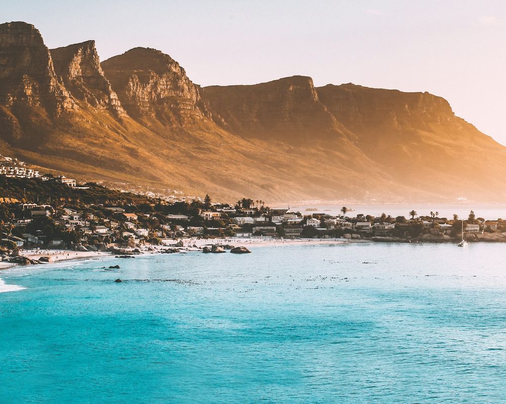 The Twelve Apostles mountain range glowing gold above the turquoise water and white beaches of Camps Bay